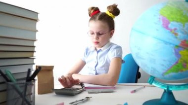 Okula dönersek, bir kız masasında oturur ve hesap makinesinde hesaplamalar yapar. Portre.