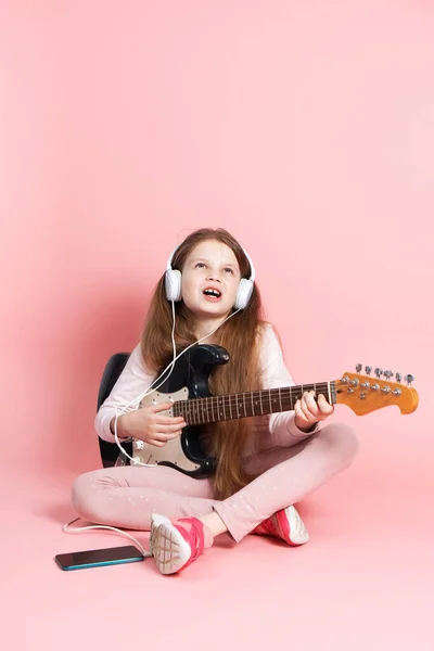 Music lessons: a schoolgirl learns to play the electric guitar.