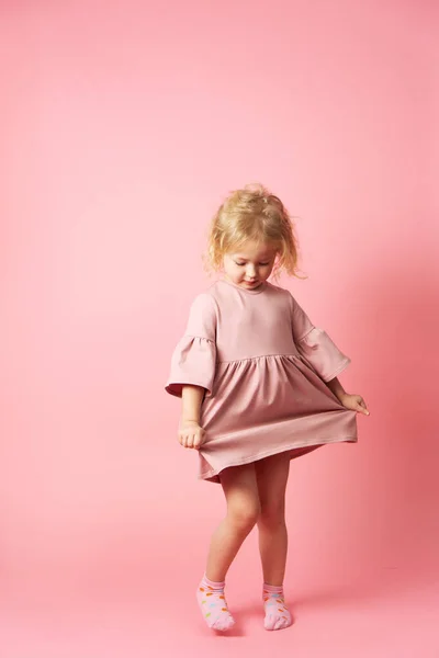 Una niña con un vestido rosa está girando y demostrando su atuendo . — Foto de Stock