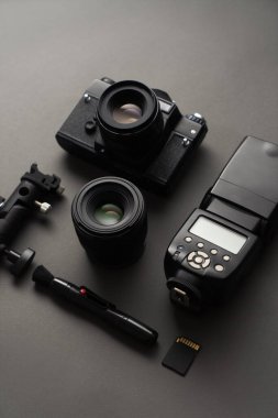 Minimalistic black: view of the camera, flash, lens and cleaning tool.