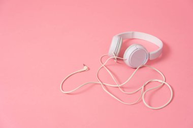 Müzik: Pembe arka planda beyaz kulaklık. Pembe arkaplanda kopyalama alanı olan yakın plan.