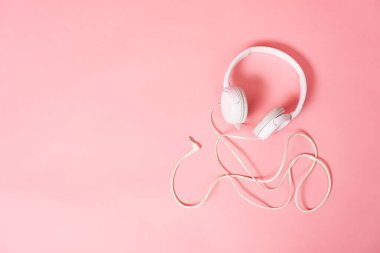 Müzik: Pembe arka planda beyaz kulaklık. Pembe arkaplanda kopyalama alanı olan yakın plan.
