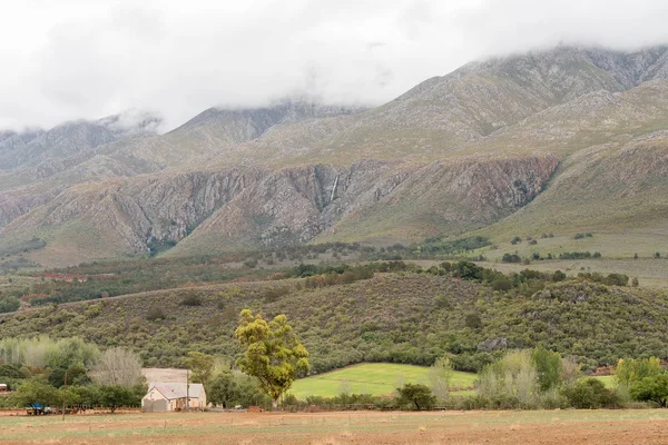 Farm landscape with waterfall on the cloud covered Swartberg — Stock Photo, Image