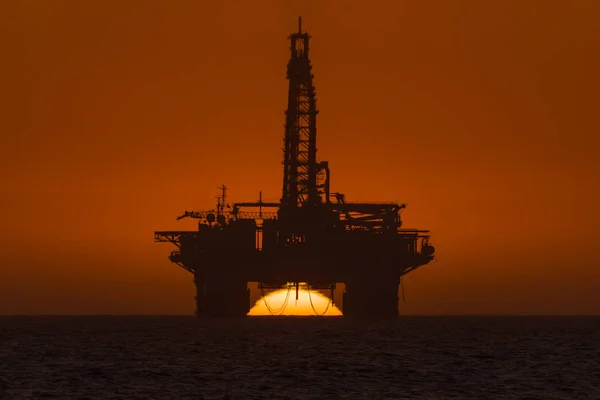 Sun setting behind oil drilling platform at Longbeach in Namibia