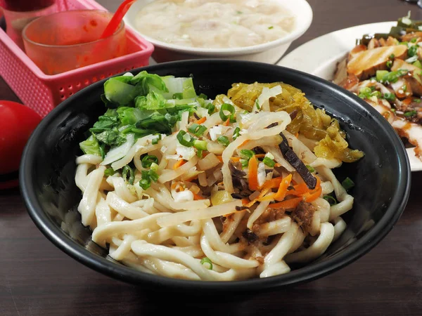 A bowl of dry noodles on wood table