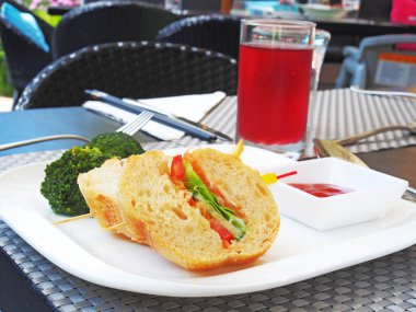 Sebzeli sandviç, patates kızartması ve ketçaplı beyaz tabak.