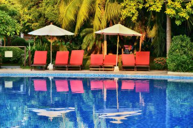  Tropikal bir tatil köyündeki havuzun kenarında beyaz şemsiye. 