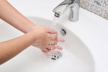 Suyun altında sabunla ellerini yıkamak..   