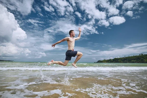 Gioioso uomo che salta sulla spiaggia — Foto Stock