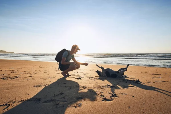 Mladý muž se psem na pláži — Stock fotografie