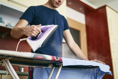 Rutin ev işleri. Evde ütü yapan bekar bir adam var..