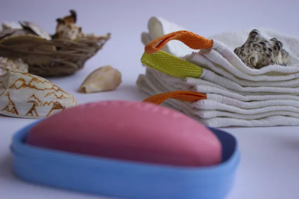 Mavi sabunlukta pembe el sabunu. Havlular onun yanında yatıyor. İç tarafında bir demet lavanta ve deniz kabuğu var. Mavi bir sabun kabı. Havlular onun yanında yatıyor. İç tarafında bir demet lavanta ve deniz kabuğu var..