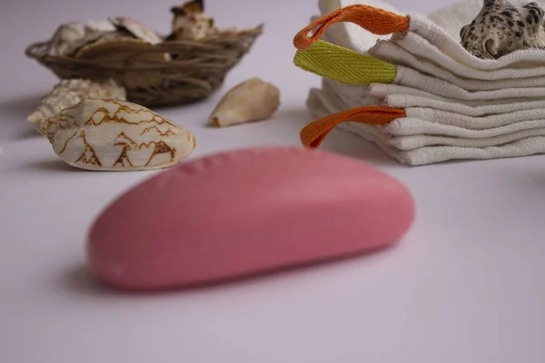 Mavi sabunlukta pembe el sabunu. Havlular onun yanında yatıyor. İç tarafında bir demet lavanta ve deniz kabuğu var. Mavi bir sabun kabı. Havlular onun yanında yatıyor. İç tarafında bir demet lavanta ve deniz kabuğu var..