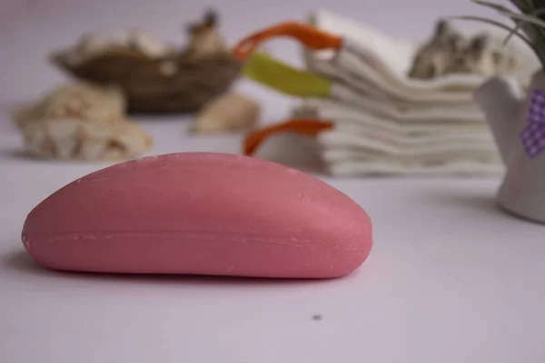 Mavi sabunlukta pembe el sabunu. Havlular onun yanında yatıyor. İç tarafında bir demet lavanta ve deniz kabuğu var. Mavi bir sabun kabı. Havlular onun yanında yatıyor. İç tarafında bir demet lavanta ve deniz kabuğu var..