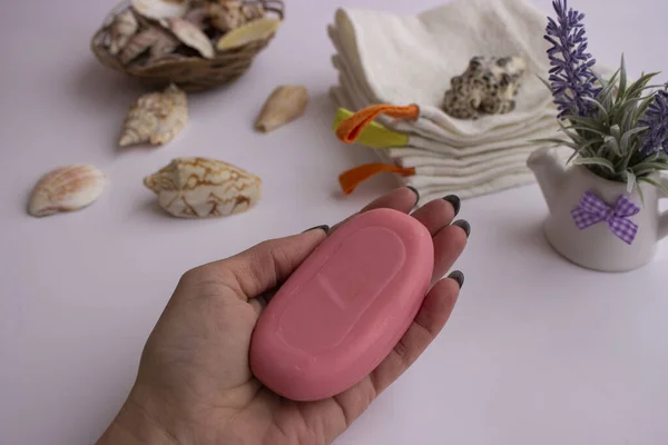 Mavi sabunlukta pembe el sabunu. Havlular onun yanında yatıyor. İç tarafında bir demet lavanta ve deniz kabuğu var. Mavi bir sabun kabı. Havlular onun yanında yatıyor. İç tarafında bir demet lavanta ve deniz kabuğu var..