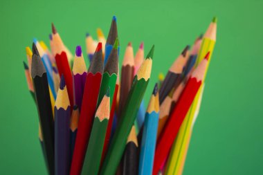 Yeşil arka plan üzerine çizim yapmak için kalemler. Renkli kalemler. Ofis malzemeleri.