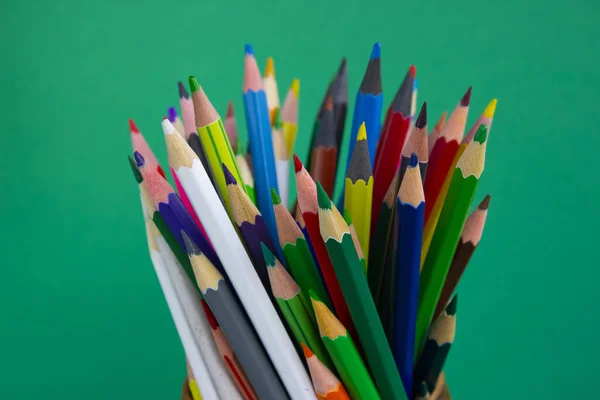 Pencils for drawing on a green background. Colored pencils. Office supplies.