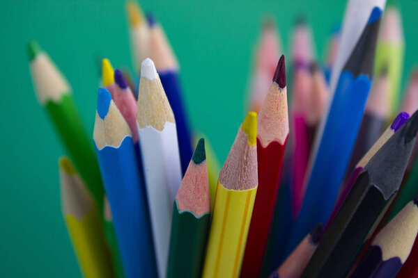 Pencils for drawing on a green background. Colored pencils. Office supplies.