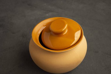 Yemek pişirmek için kil saksıları. Açık renkli çömlekler. Karanlık bir arka planda yemek pişirmek. Kızartma için kapağı olan bir kil kap. Aşçılık için eski mutfak gereçleri.