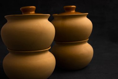 Yemek pişirmek için kil saksıları. Açık renkli çömlekler. Karanlık bir arka planda yemek pişirmek. Kızartma için kapağı olan bir kil kap. Aşçılık için eski mutfak gereçleri.