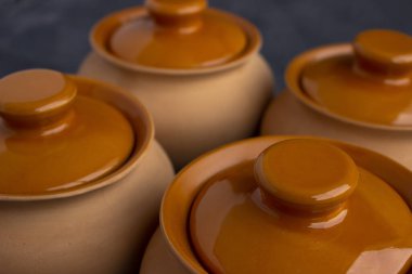 Yemek pişirmek için kil saksıları. Açık renkli çömlekler. Karanlık bir arka planda yemek pişirmek. Kızartma için kapağı olan bir kil kap. Aşçılık için eski mutfak gereçleri.