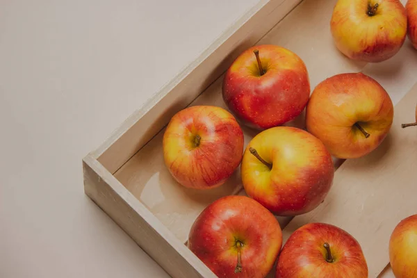 The apples are in a white wooden box on a white background. Red and yellow ripe apples.