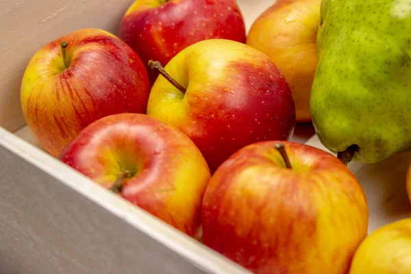 The apples are in a white wooden box on a white background. Red and yellow ripe apples.