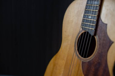 Kopya alanı olan siyah bir arkaplanda dinlenen akustik gitar