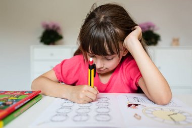 Kız ödevini yapıyor.