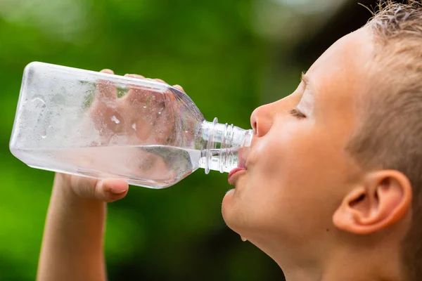 Молодий хлопець п'є воду з пляшки — стокове фото