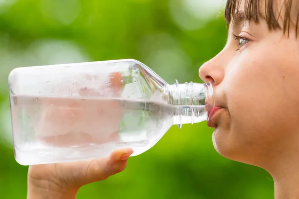 Ребенок пьет чистую воду из прозрачной пластиковой бутылки — стоковое фото
