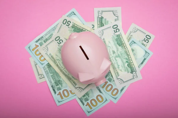 貯金箱とピンクのパステル調の背景にお金 — ストック写真