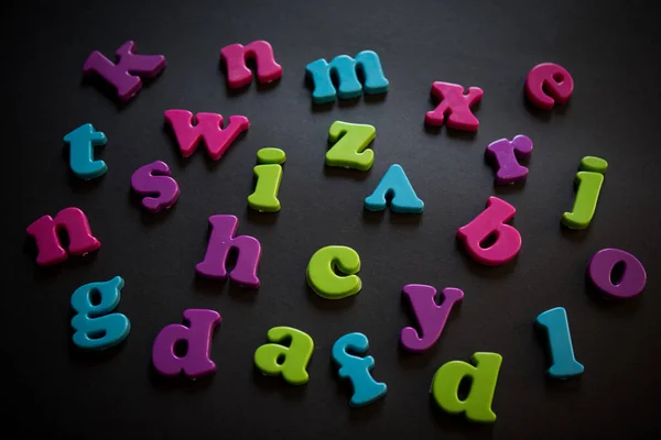 Colorful plastic alphabet letters on a black background — Stock Photo, Image