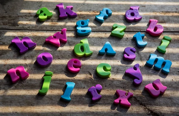 Colorful plastic alphabet letters on a wooden background. — Stock Photo, Image