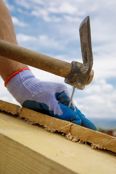 Builder's hands hammering nail into wood — Stock Photo, Image