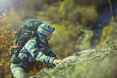Sırt çantası ile etkin hiker kayaya tırmanıyor