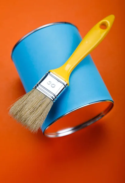 Can of blue paint and paintbrush on orange background — Stock Photo, Image