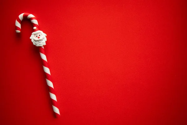 Bastoncino di zucchero natalizio con ornamento Babbo Natale su bsckgrounf rosso — Foto Stock