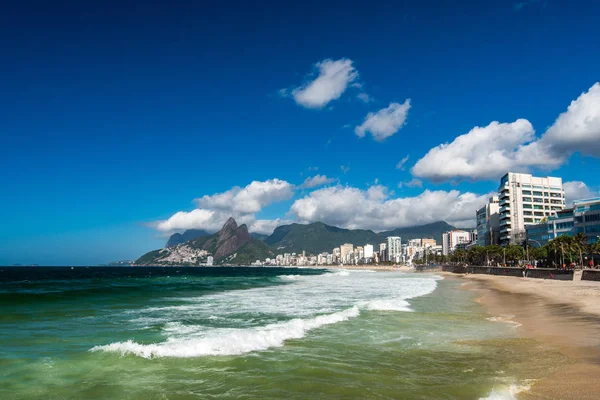 海浪在海洋在依帕内玛海滩与美丽的里约热内卢山在地平线 — 图库照片