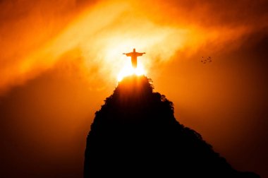 Rio de Janeiro, Brazil - January 17, 2018: The famous Rio de Janeiro landmark - Christ the Redeemer statue on Corcovado mountain. Silhouette by sunset. clipart