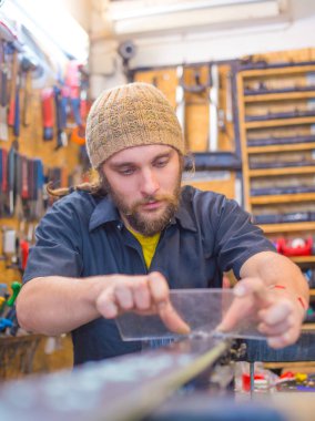 Sakallı adam atölyede el işi yapıyor.