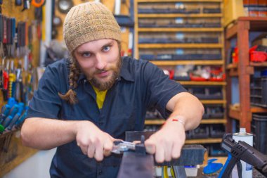 Sakallı adam atölyede kayak tamir ediyor.