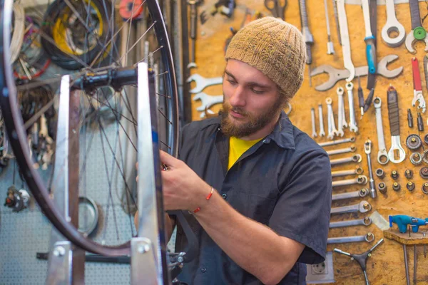 Bearded guy repairing bicycle in the workshop — Stock Photo, Image