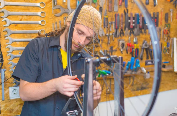 Bearded guy repairing bicycle in the workshop — Stock Photo, Image