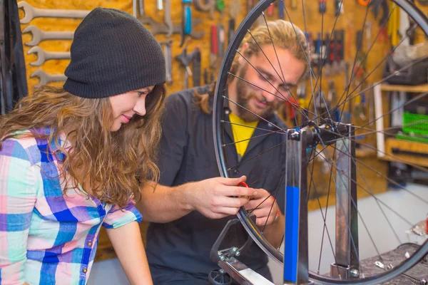 Young couple repairing bicycle in the workshop — Stock Photo, Image