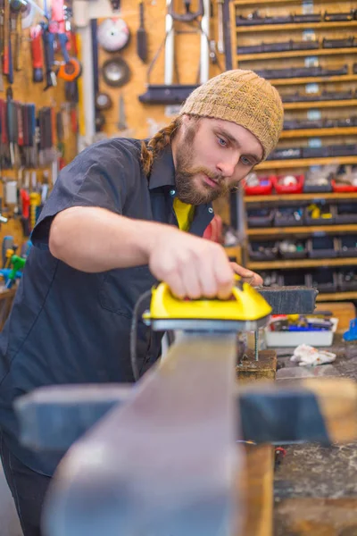 Bearded guy waxing ski in the workshop — Stock Photo, Image