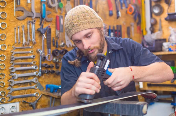 Bearded guy repairing ski in the workshop — Stock Photo, Image