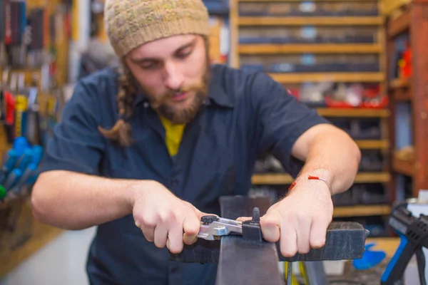 Bearded guy repairing ski in the workshop — Stock Photo, Image