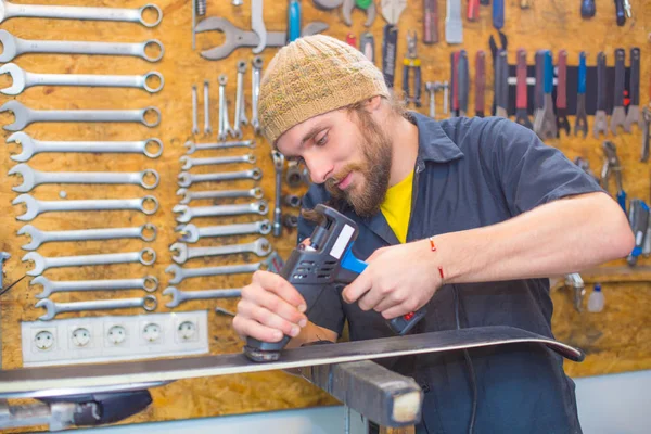 Bearded guy repairing ski in the workshop — Stock Photo, Image