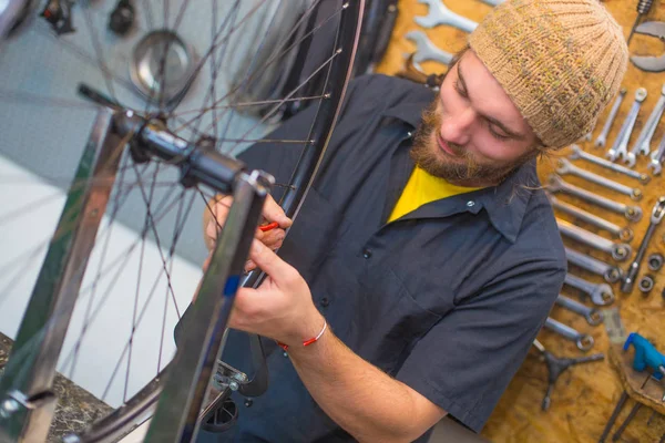 Bearded guy repairing bicycle in the workshop — Stock Photo, Image
